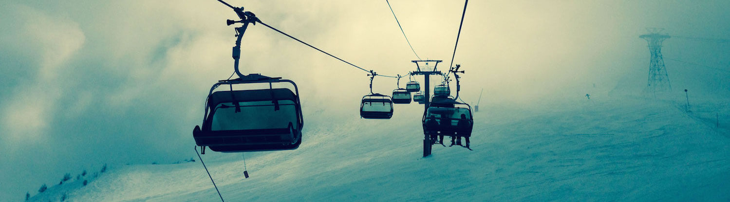Empty chairlift chairs disappearing into fog on a ski slope